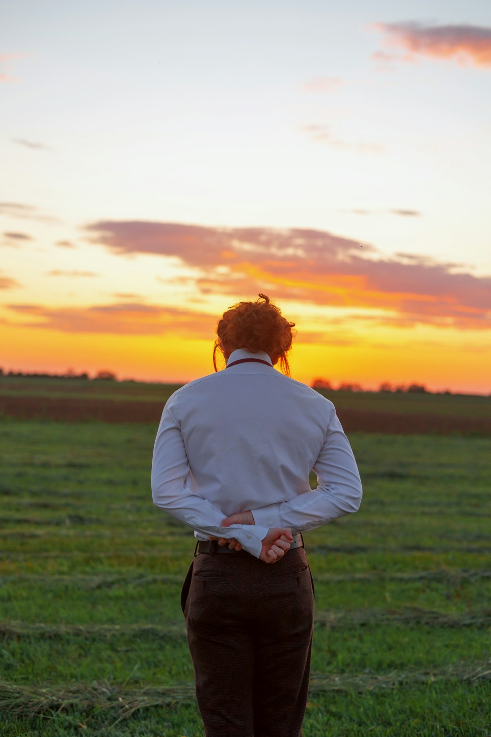 a woman standing in a field at sunset