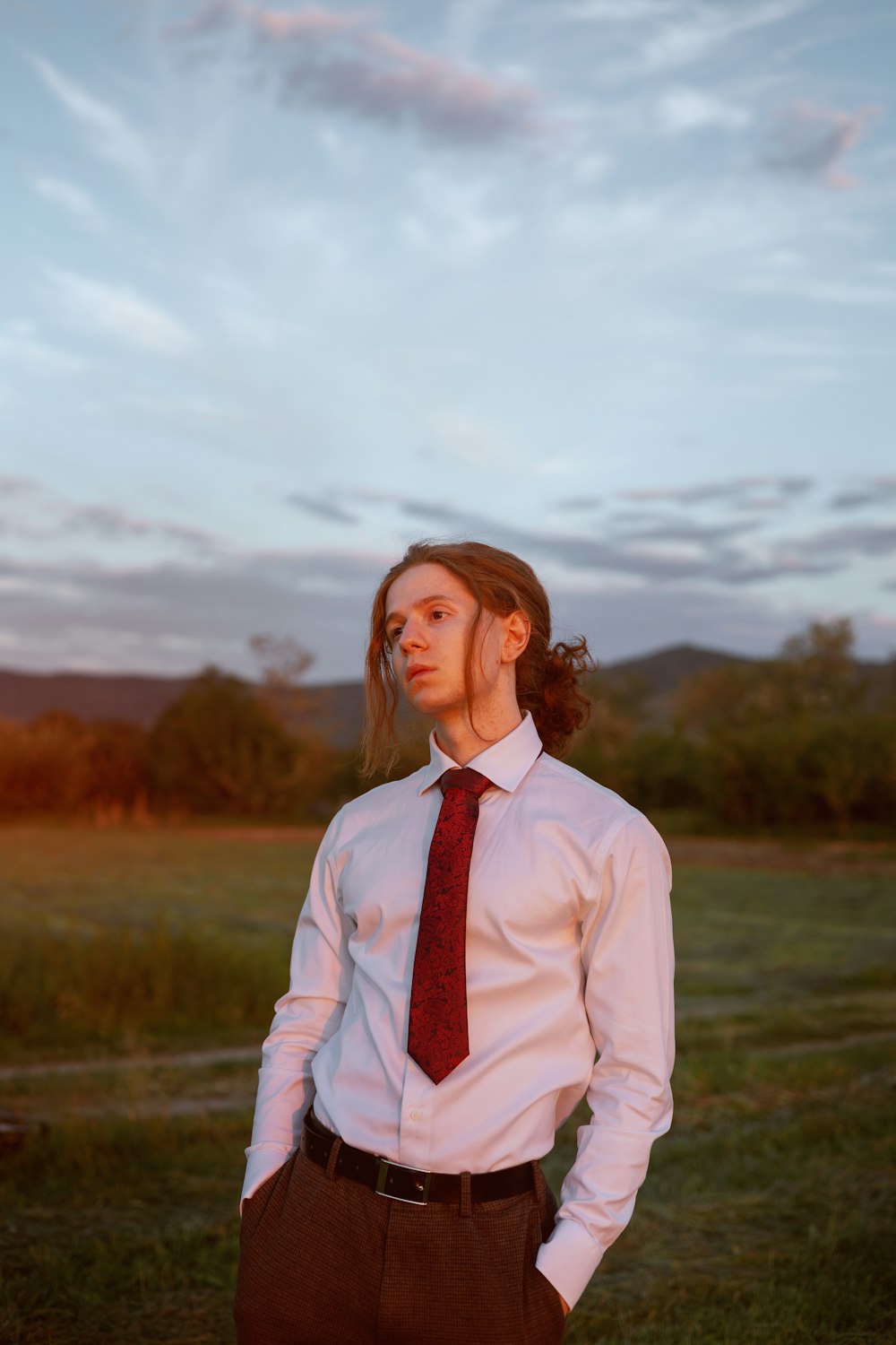 a woman in a dress shirt and tie standing in a field
