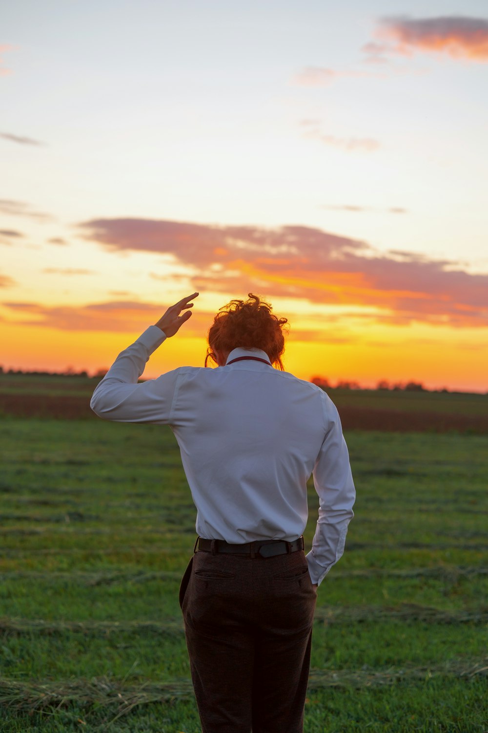 a man in a white shirt and brown pants standing in a field