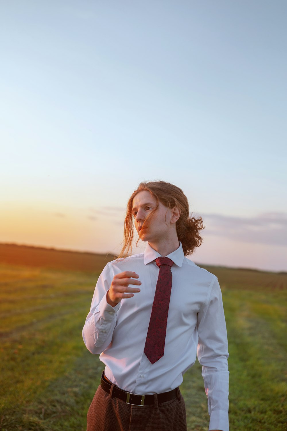 a man in a tie standing in a field