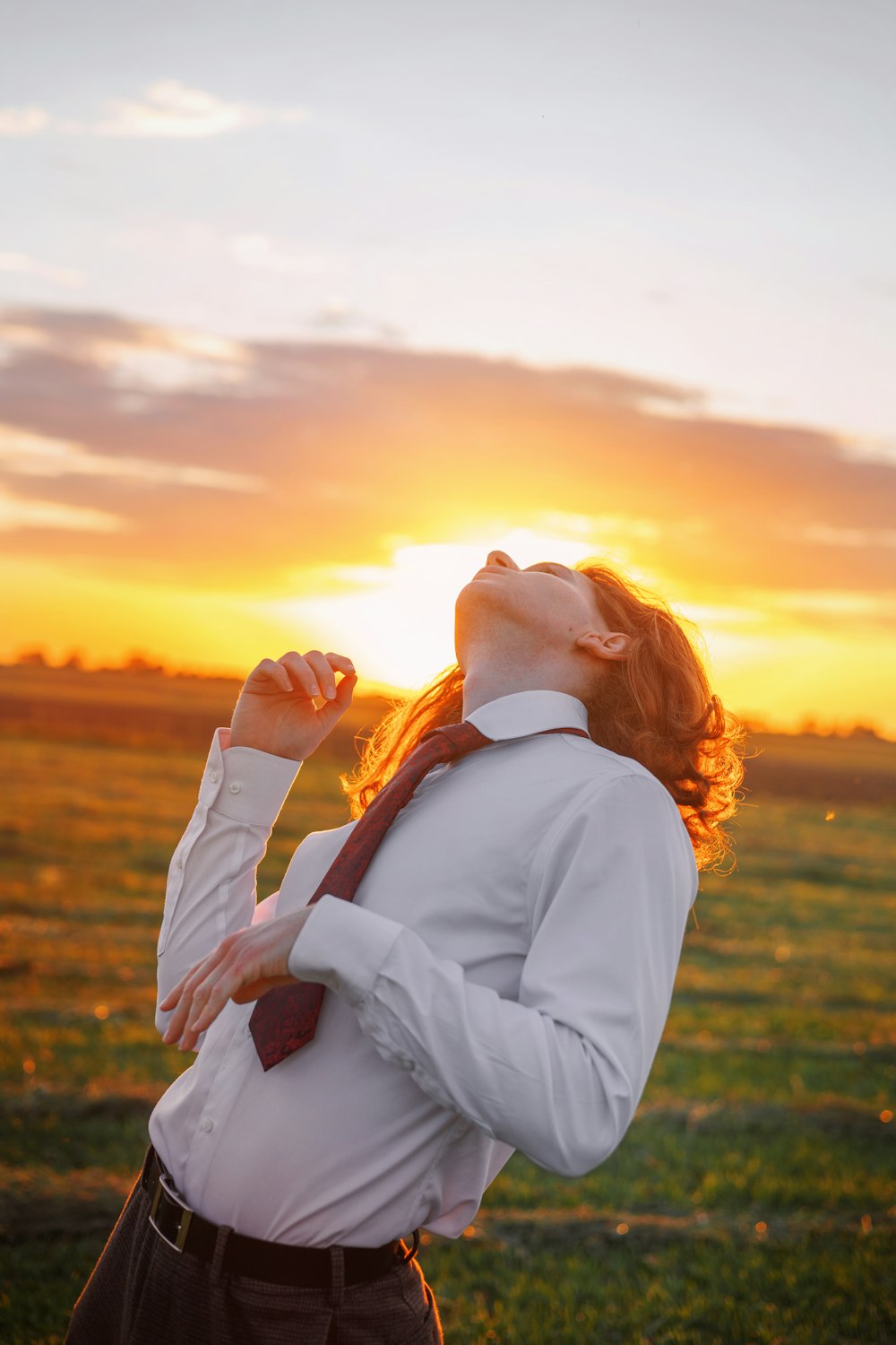 a woman standing in a field at sunset