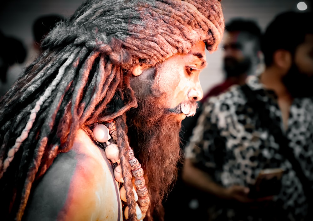 a man with dreadlocks and a beard with other people in the background