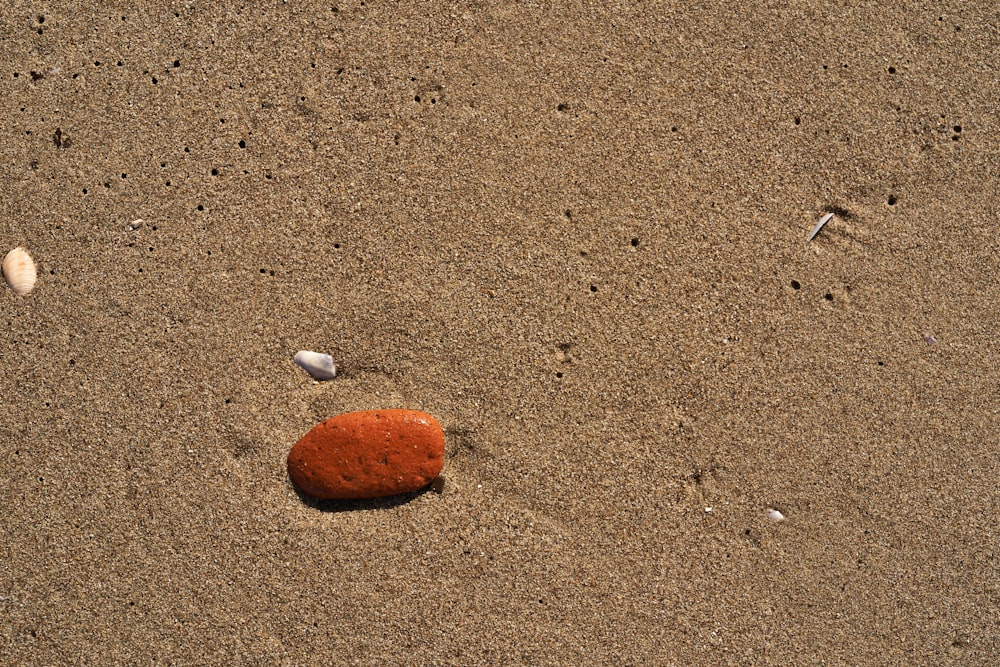 a red rock sitting on top of a sandy beach