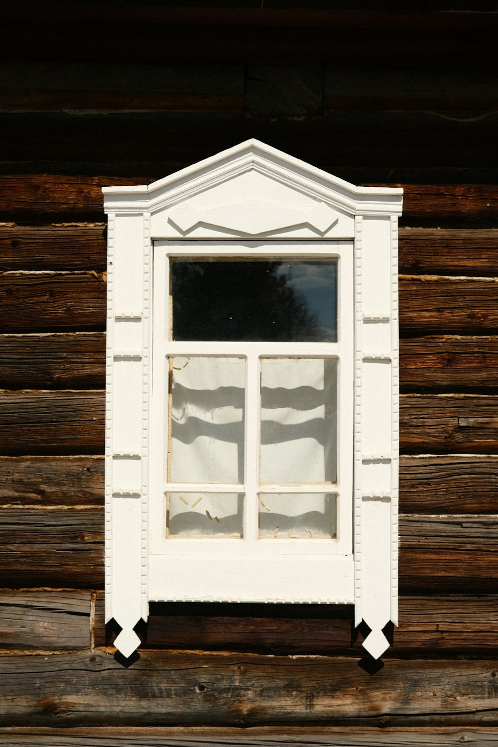 a window on a wooden wall with white trim