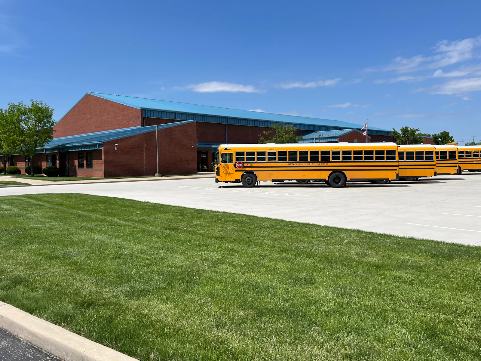 Yellow school buses parked in front of a brick school building