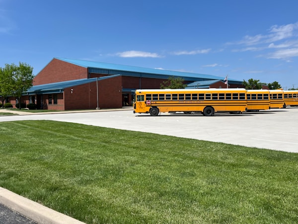 A yellow school bus parked in front of an elementary school building at dismissal time
