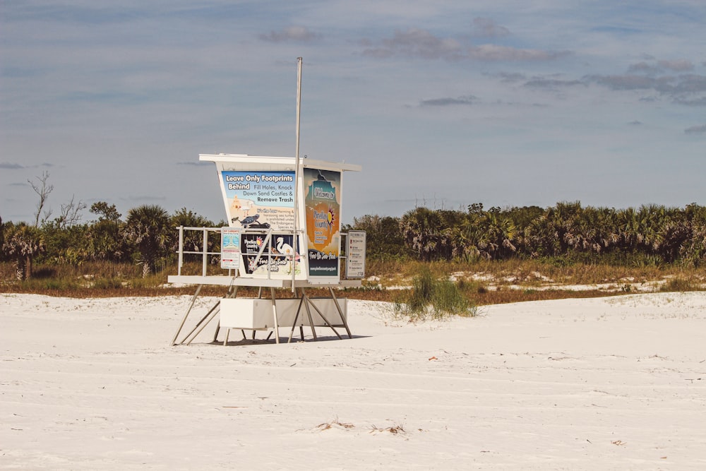 a lifeguard stand on the beach with a sign on it