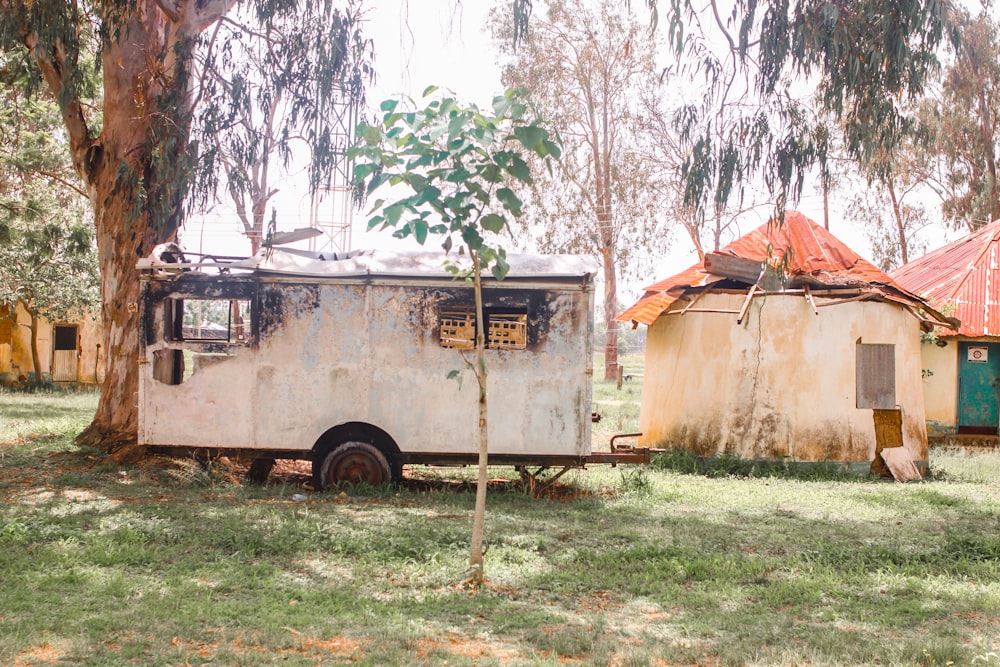 um velho trailer estacionado em um campo ao lado de uma árvore