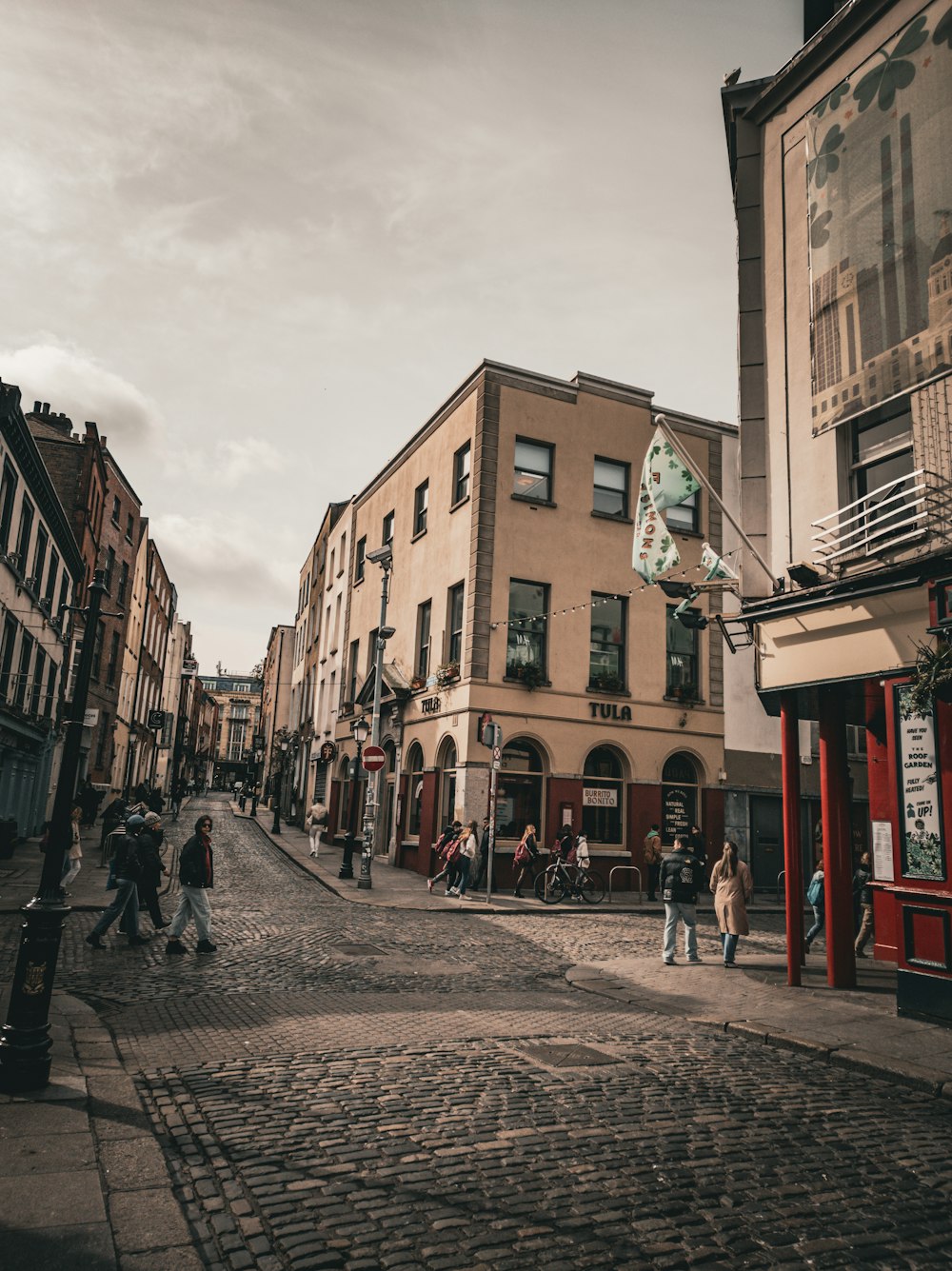 a group of people walking down a street next to tall buildings