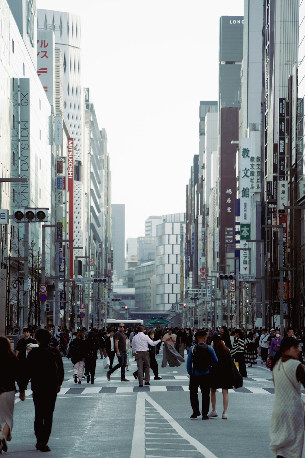 a group of people walking down a street next to tall buildings