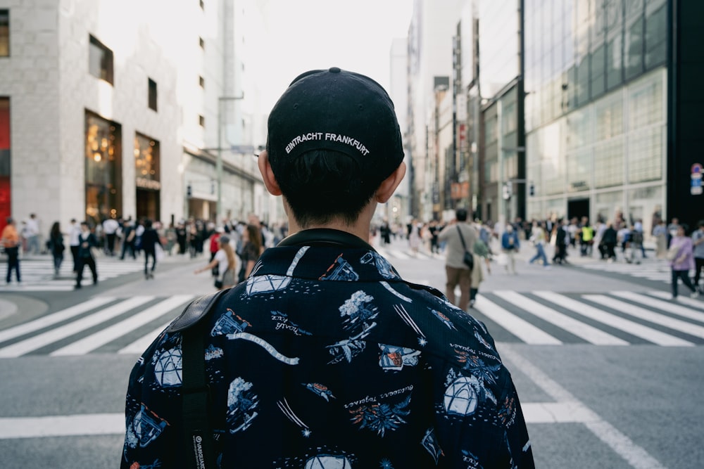 a man in a black hat is standing in the middle of the street