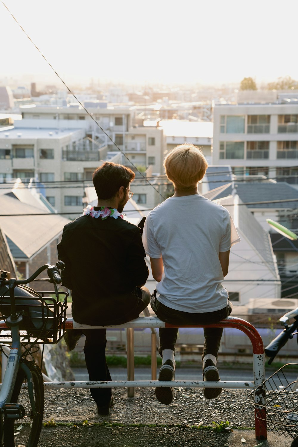 two people sitting on a bench overlooking a city