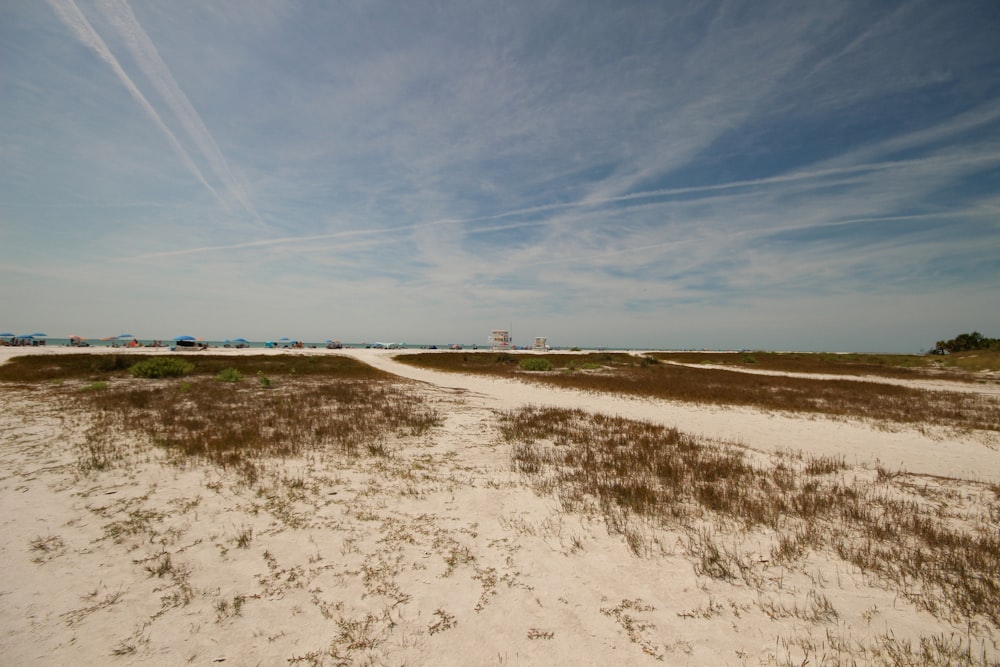 a sandy beach with a blue sky and some clouds