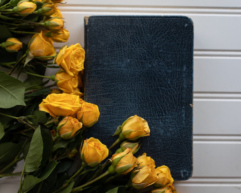 a bunch of yellow roses are next to a blue book