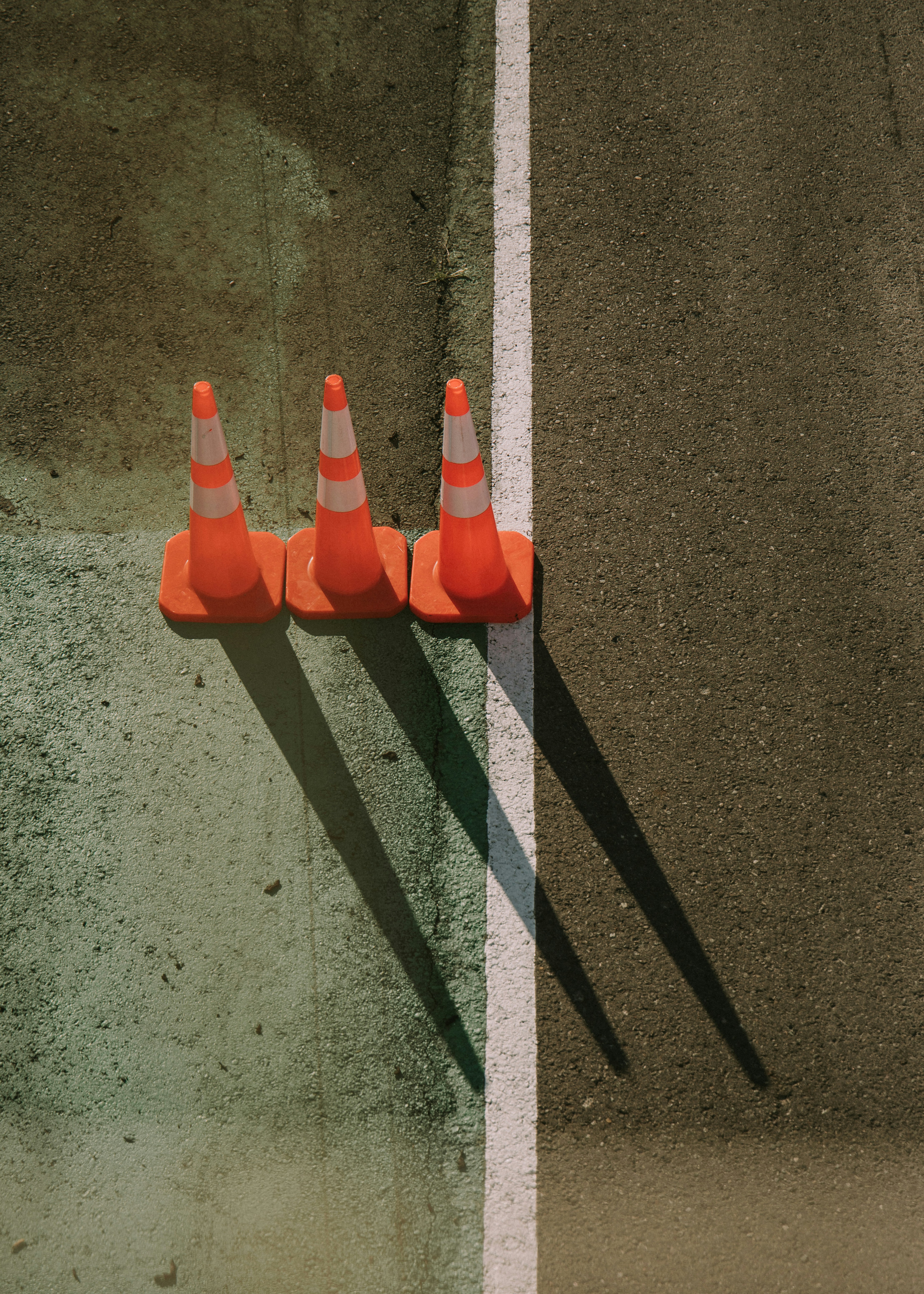 three orange traffic cones sitting on the side of a road