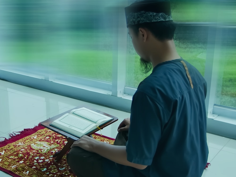 a man sitting on the floor reading a book