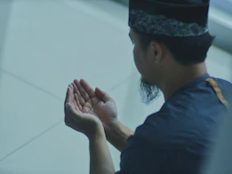 a man in a blue shirt is holding his hands together