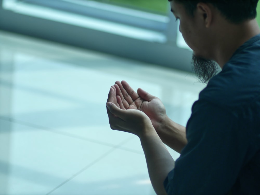 a man sitting on the ground with his hands together