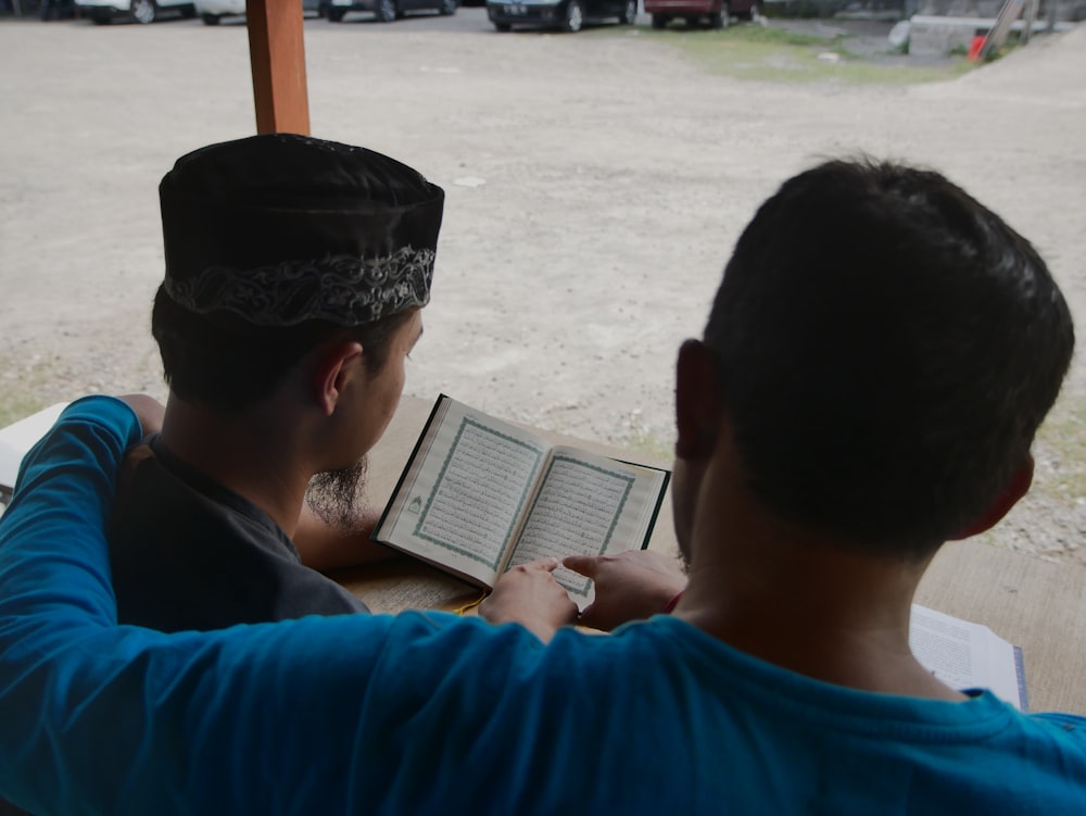 a couple of men sitting at a table with a book