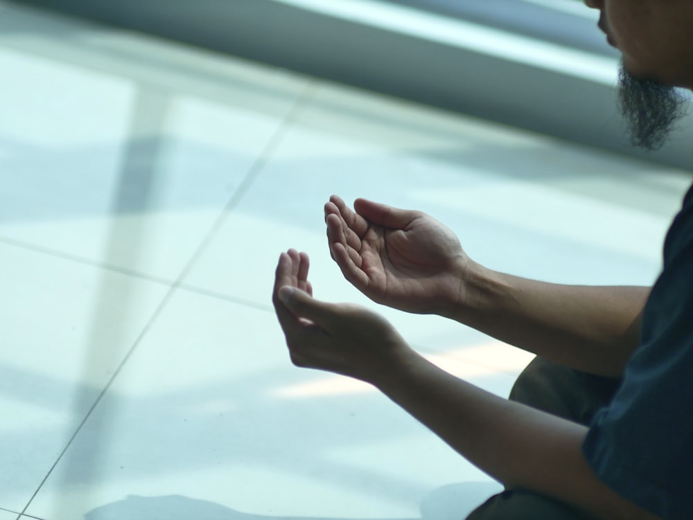 a man sitting on the floor with his hands folded