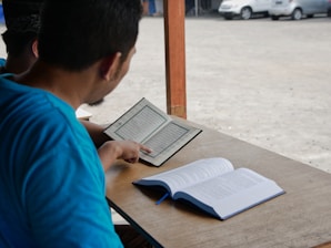Un homme assis à une table lisant un livre à une autre personne