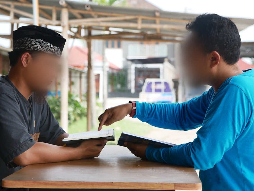 two boys sitting at a table with a book