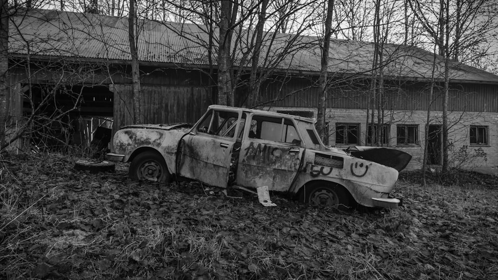a black and white photo of an old truck in front of a barn