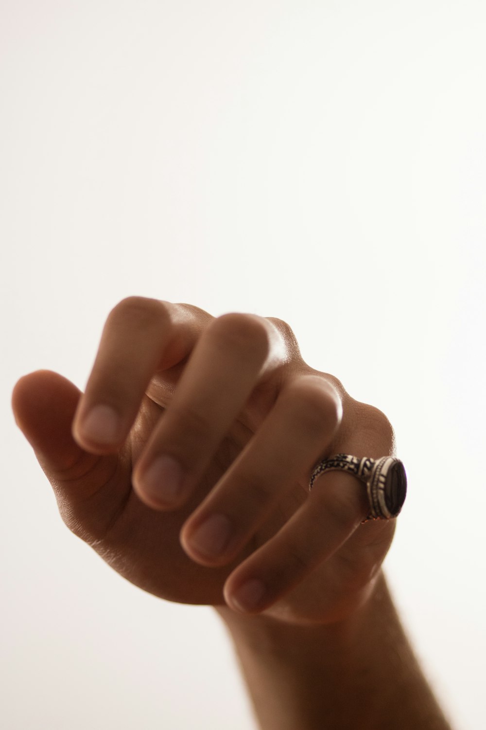 a hand with a ring on it holding something in the air