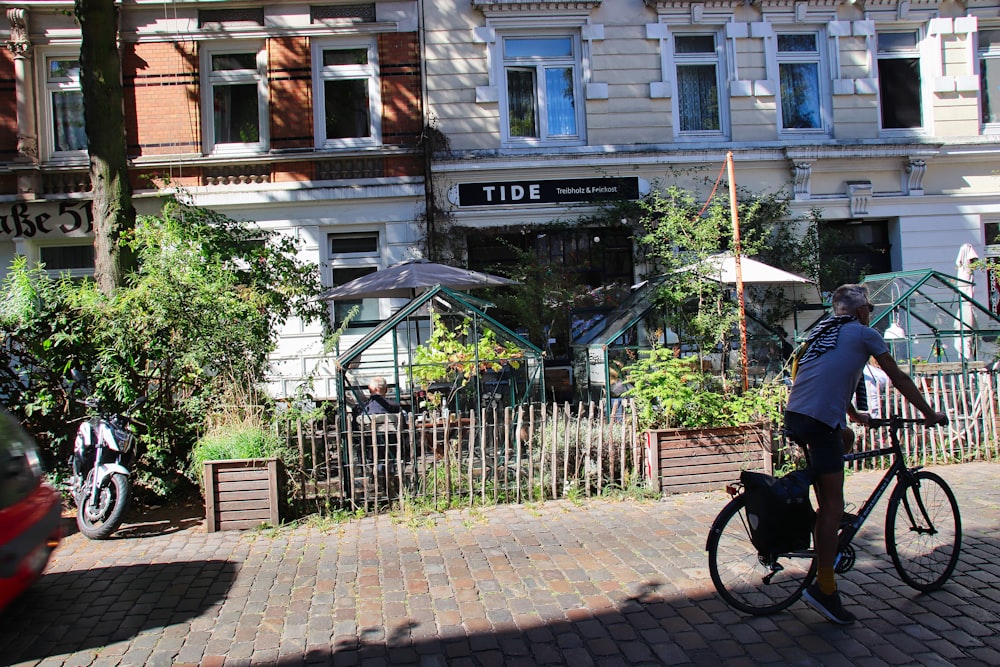 a man riding a bike down a street next to a tall building