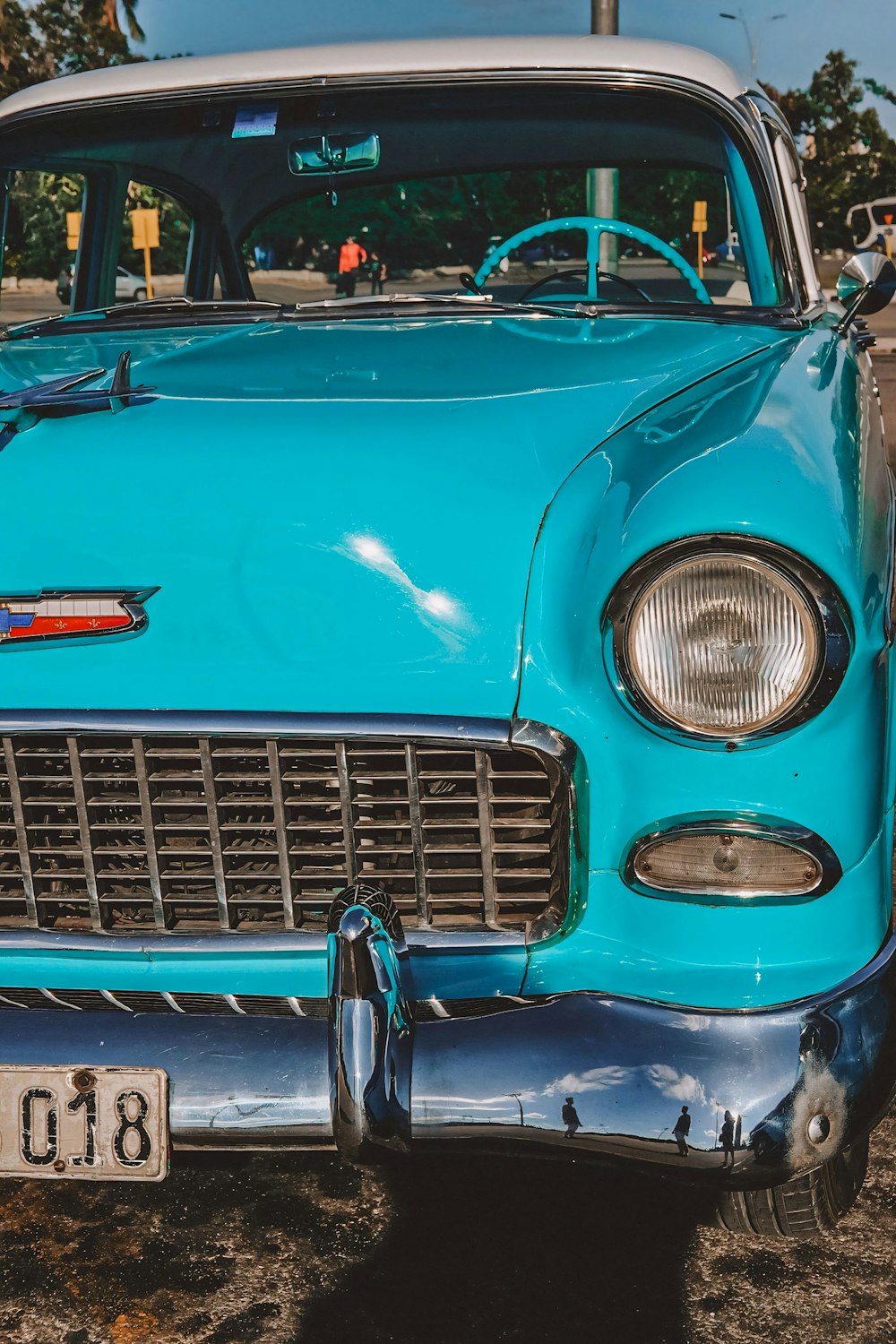 an old blue car parked on the side of the road