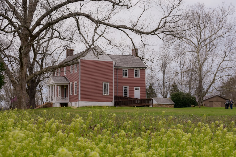 a large red house sitting in the middle of a field