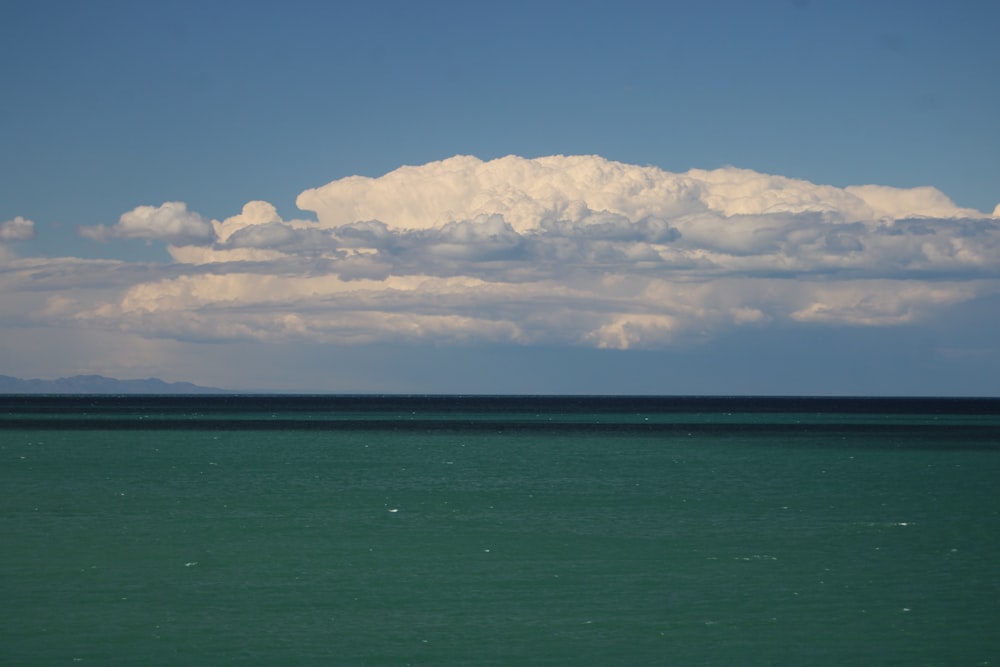 a large cloud is in the sky over a body of water