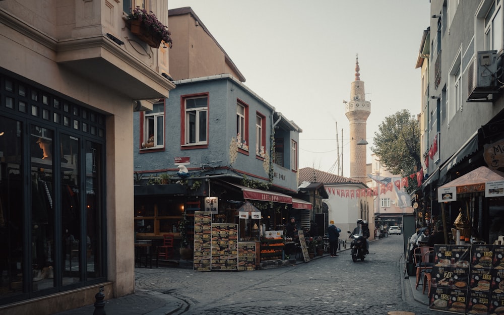 a narrow street with a tower in the background