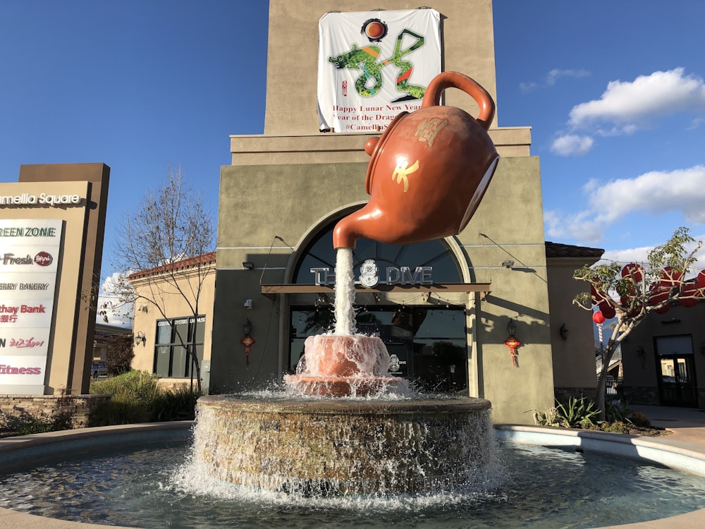 a water fountain with a tea pot on top of it