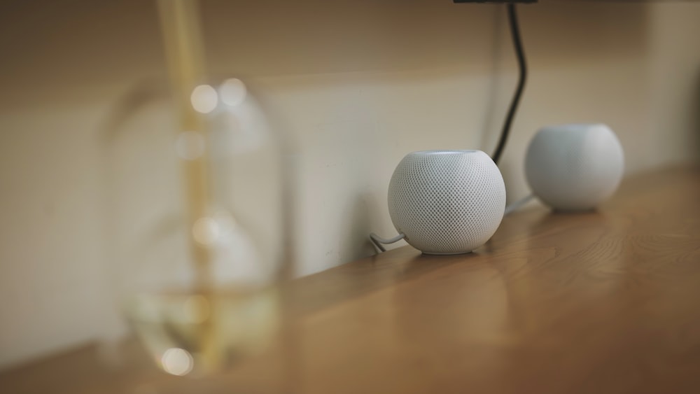 a couple of white speakers sitting on top of a wooden table