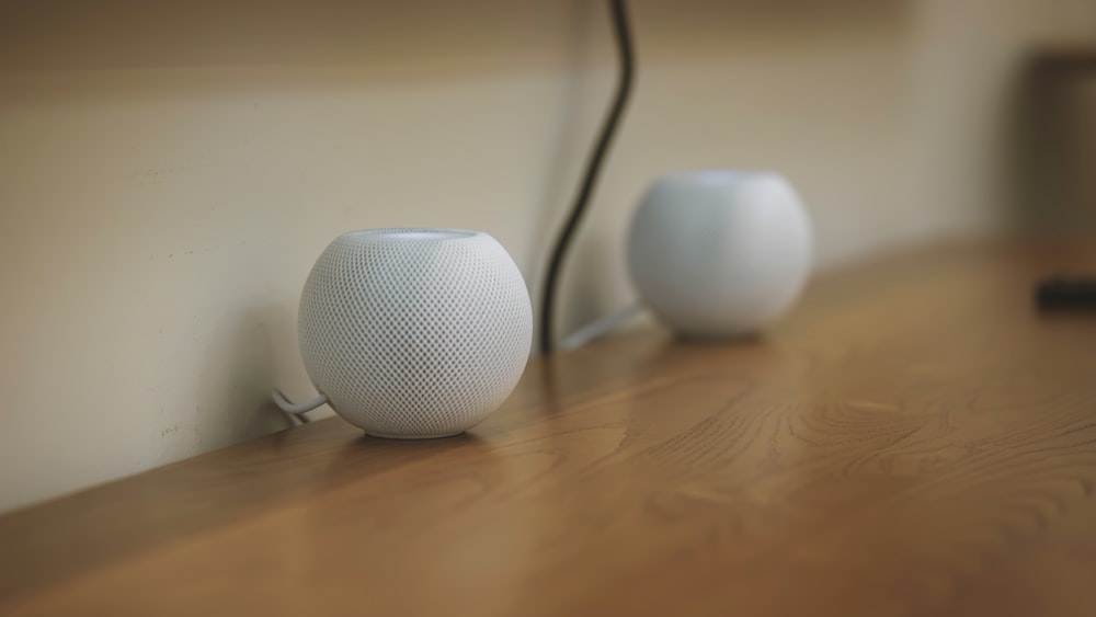 a couple of white speakers sitting on top of a wooden table