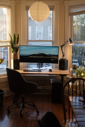 a desk with a computer on it in front of a window
