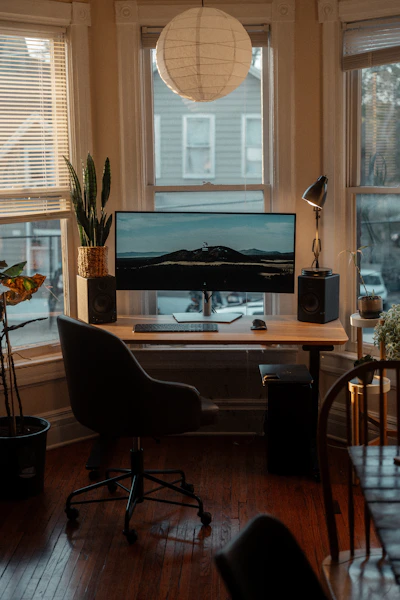 a desk with a computer on it in front of a window