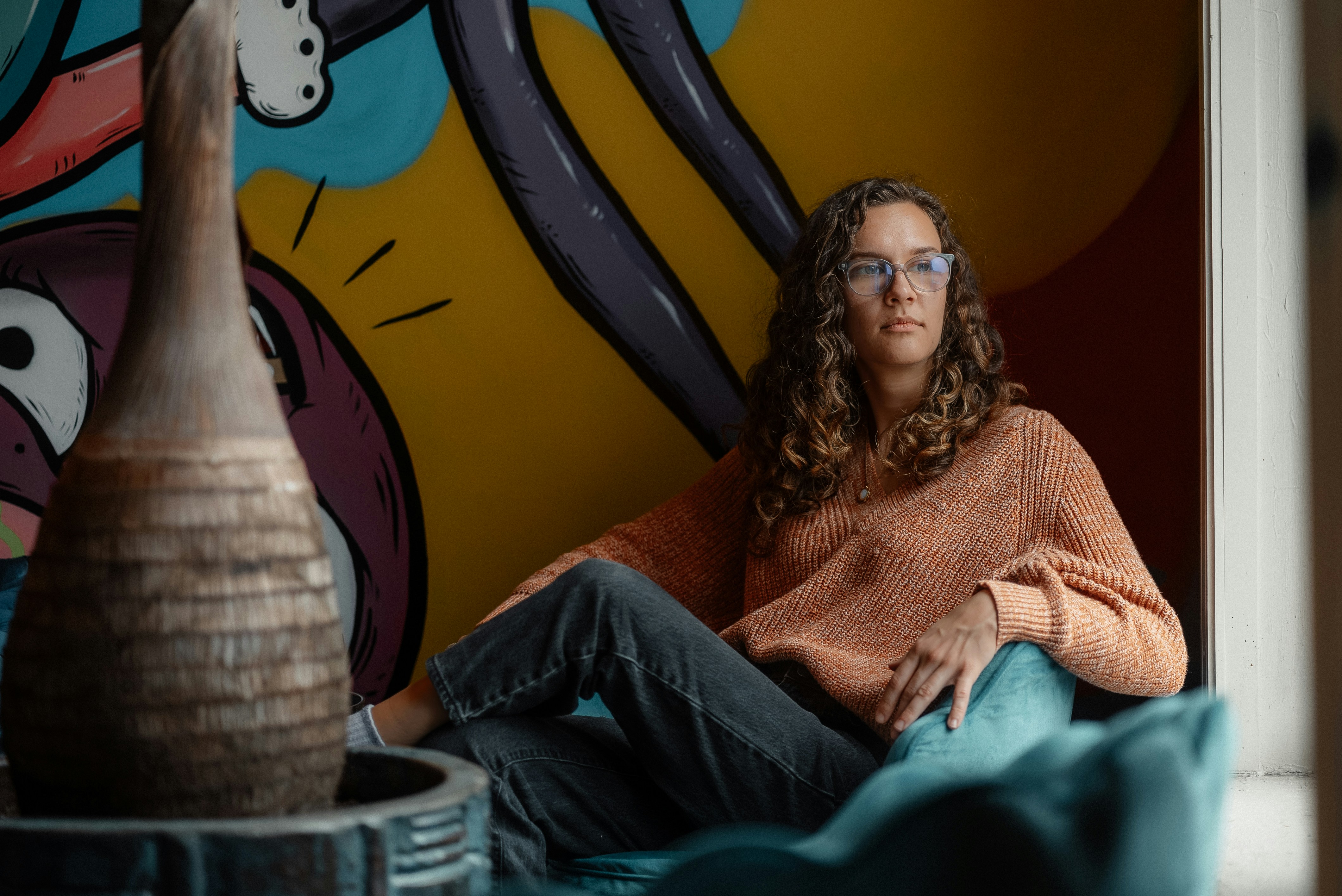 a woman sitting on a couch next to a vase