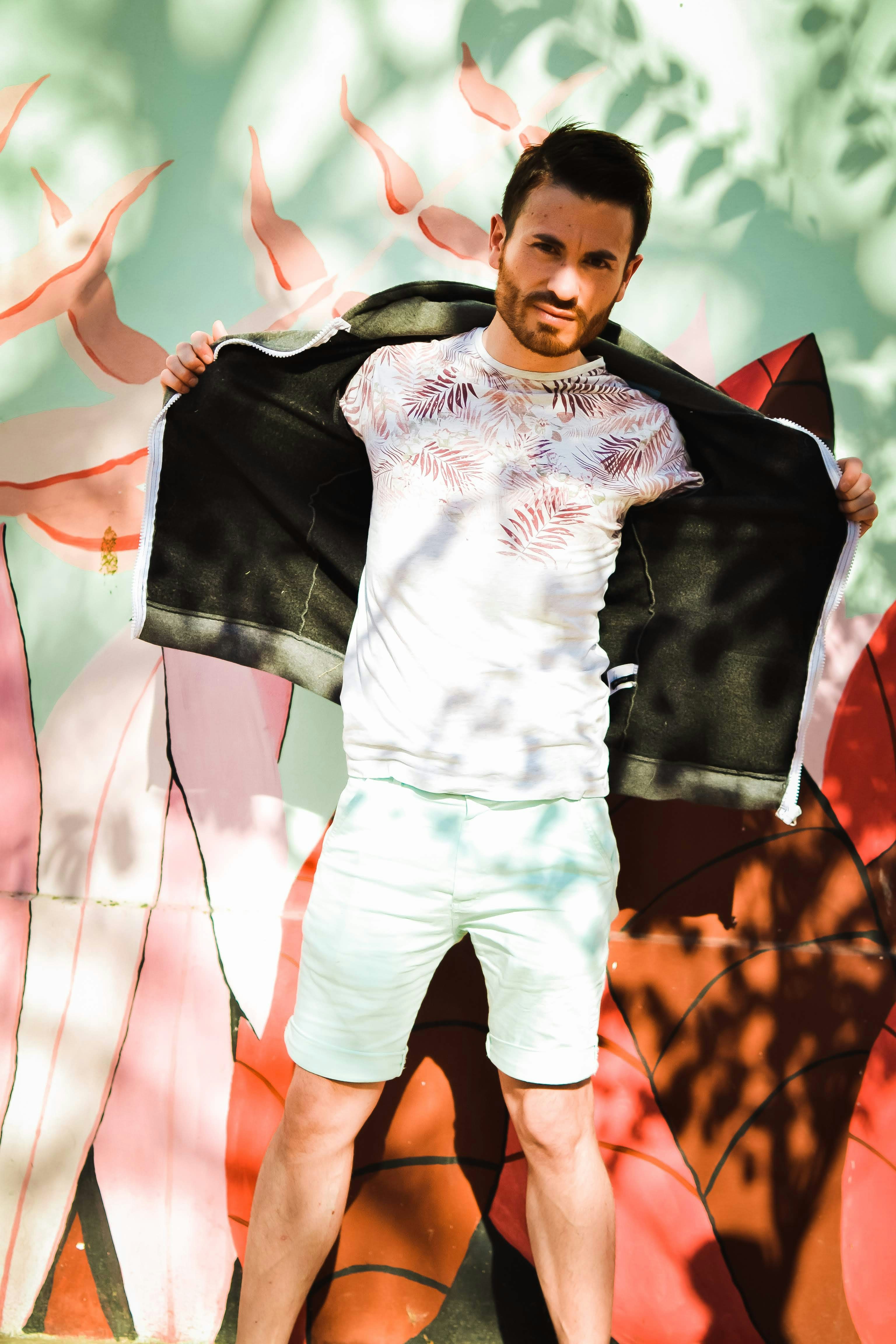 a man standing in front of a mural holding a jacket