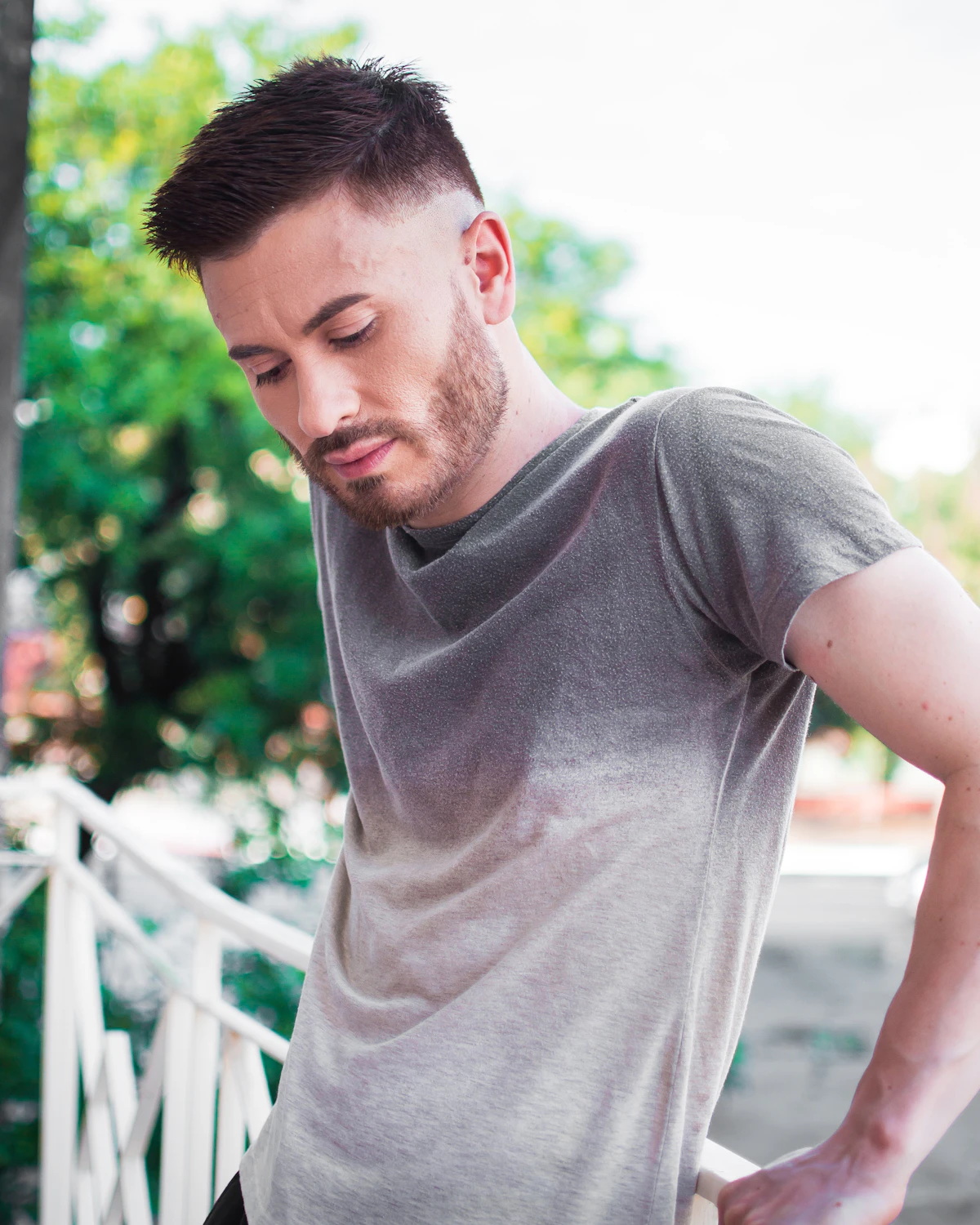 Man standing outdoors with his hand braced against his lower back, looking down, illustrating back pain that regenerative medicine can address.