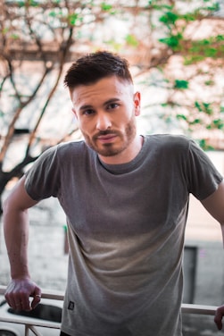 a man standing next to a fence with his hands on his hips