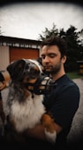 a man holding a dog wearing a muzzle