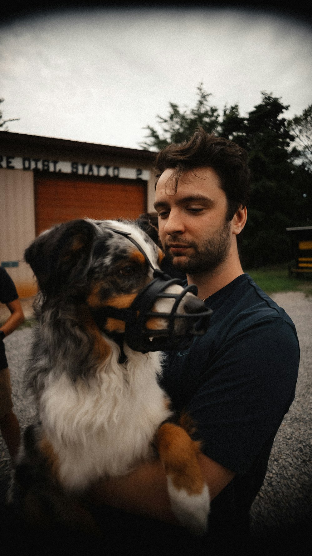 a man holding a dog wearing a muzzle