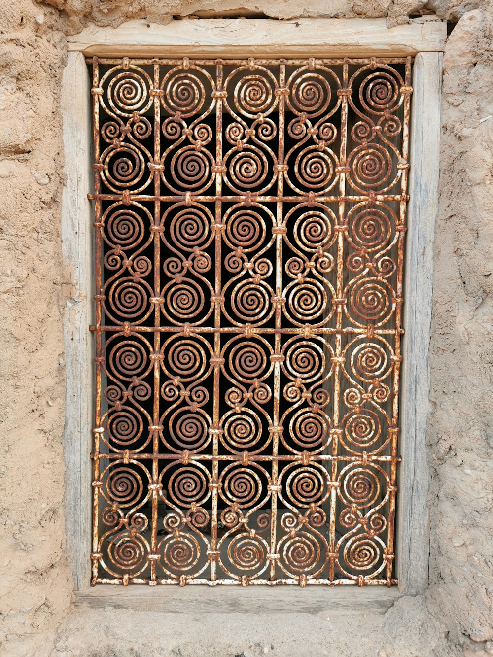 a window with a metal grate on a stone wall