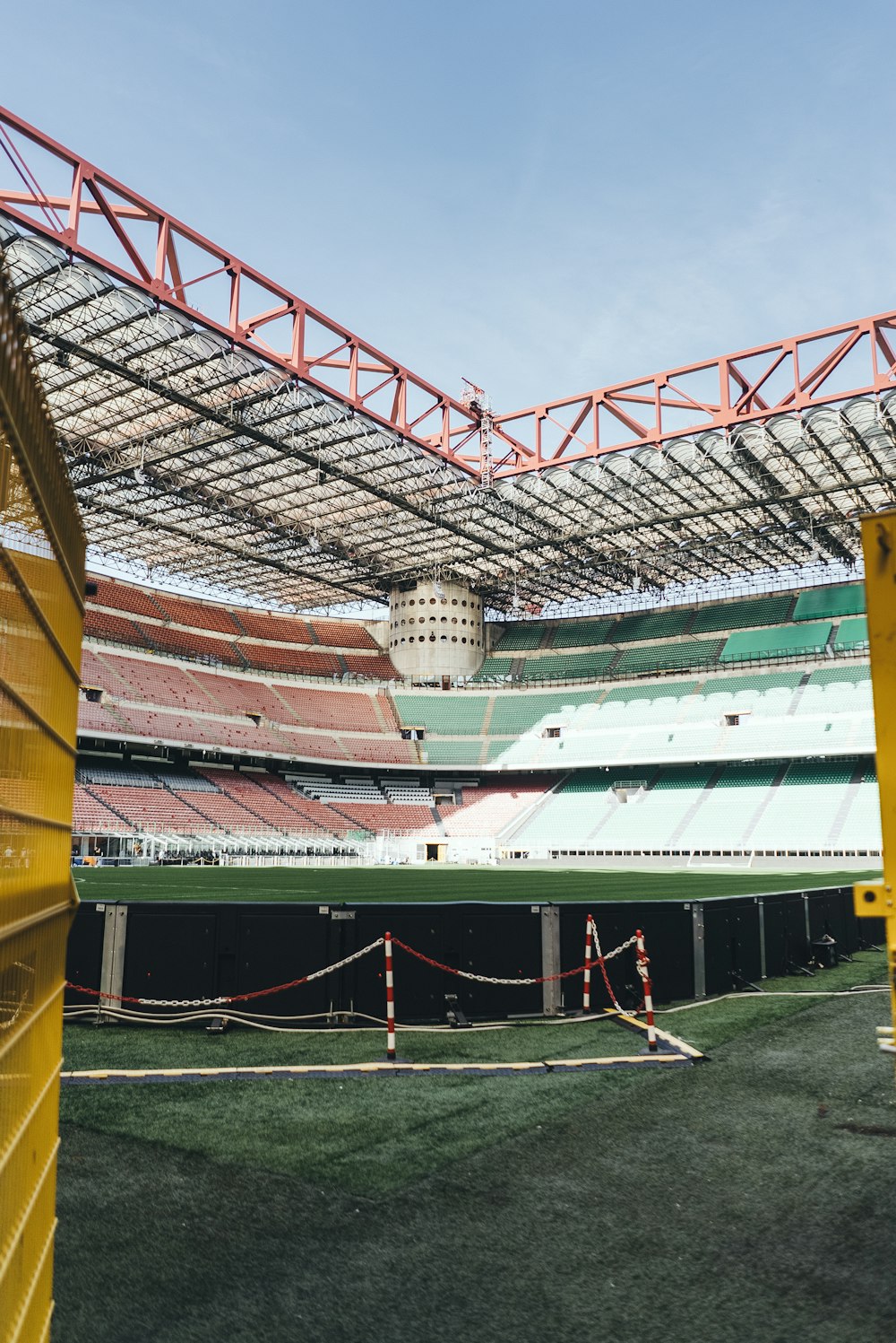 an empty stadium with grass and yellow barriers