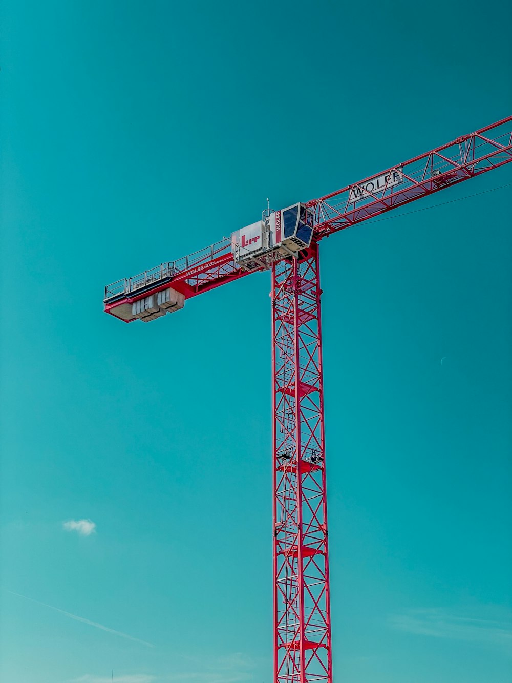 a large red crane sitting on top of a lush green field