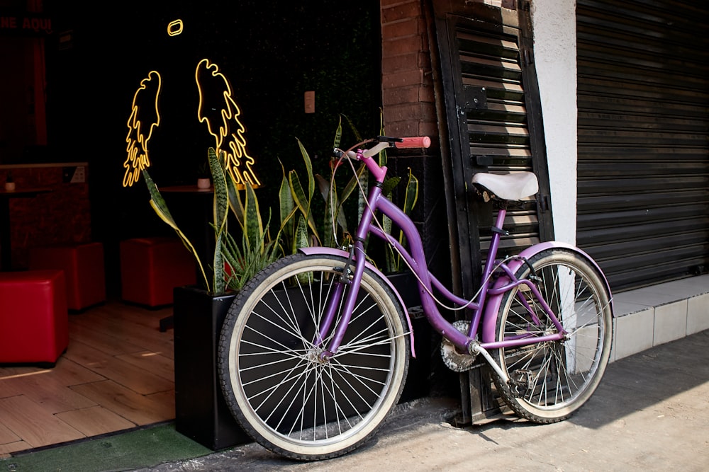 Una bicicleta morada estacionada junto a un edificio