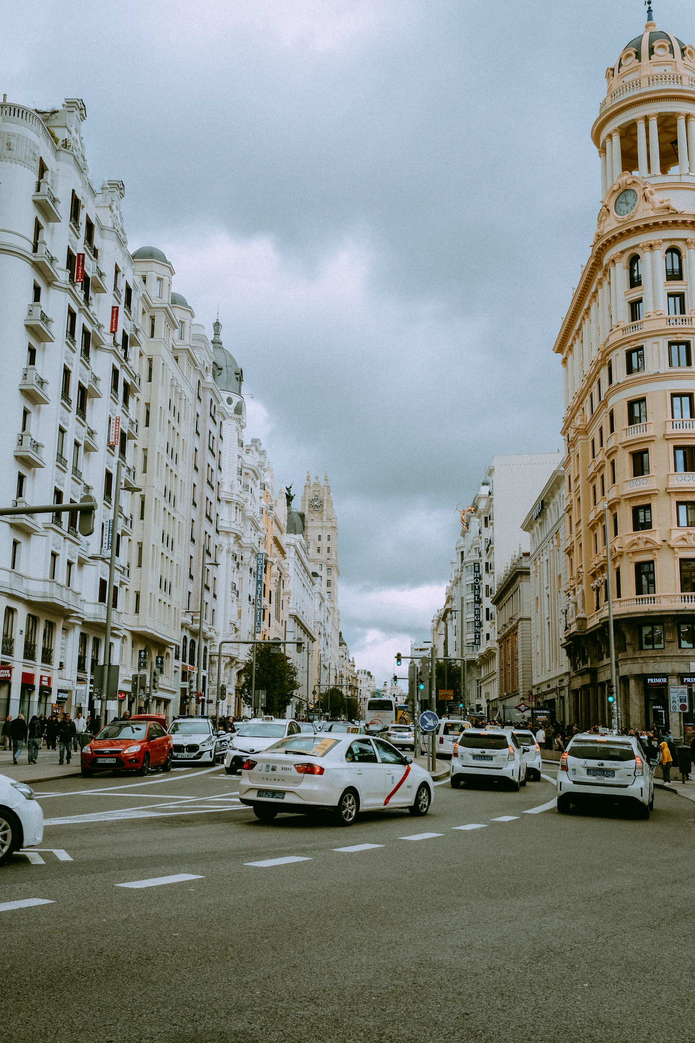 White taxis with a red stripe on Gran Vía in Madrid, between ornate stone façades