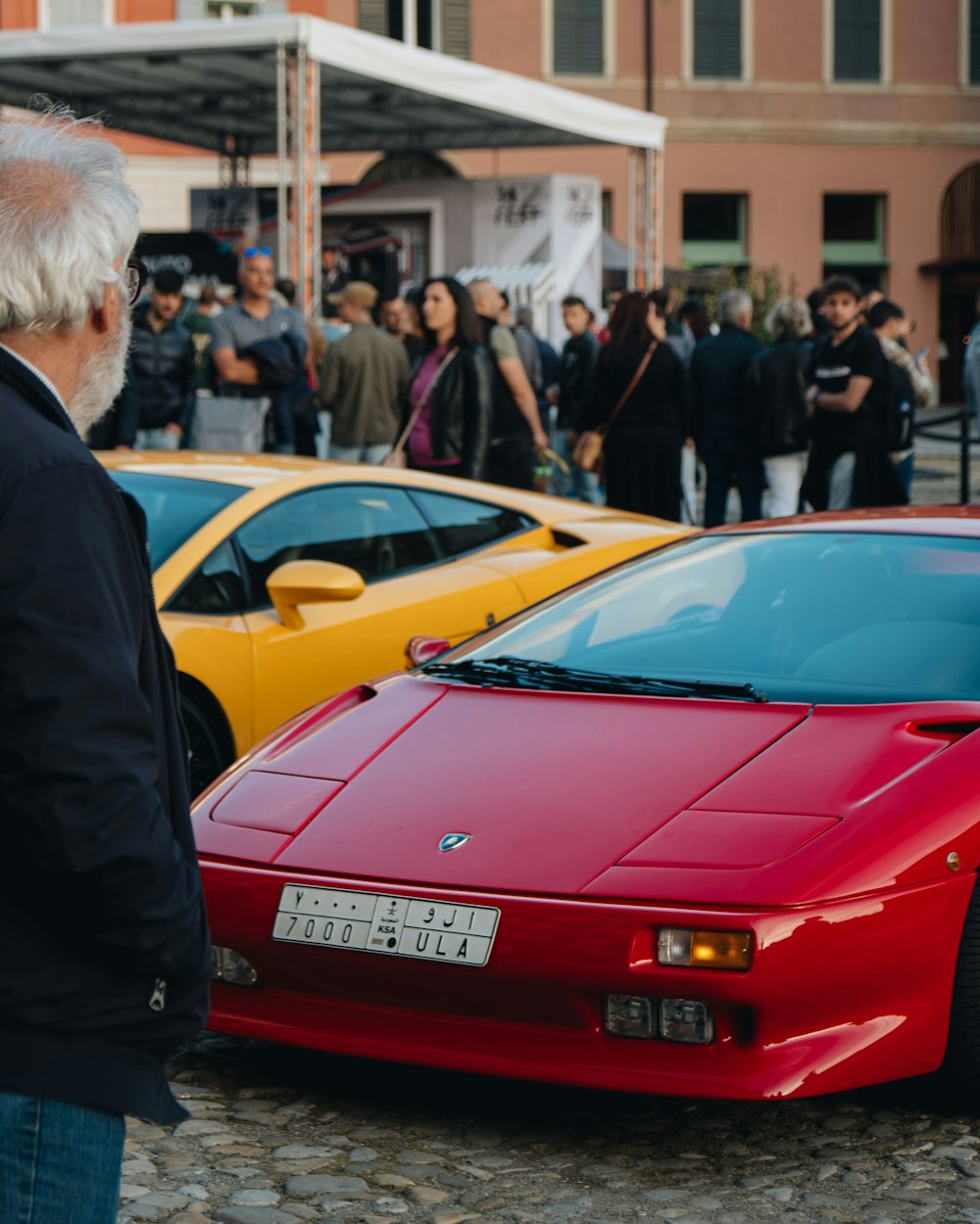 Un hombre de pie junto a un coche deportivo rojo